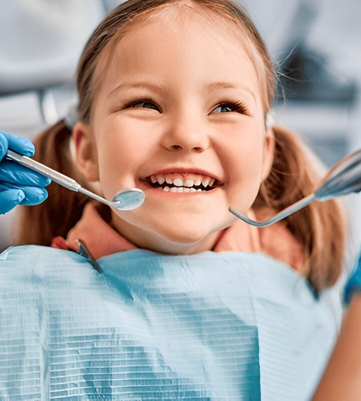 Smiling young girl at the dentist having her teeth checked with dental tools